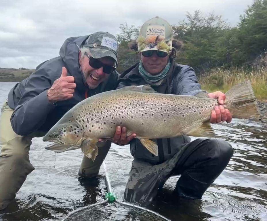 Two people holding a large caught fish.