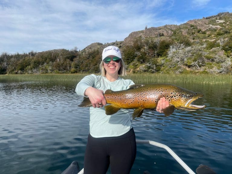 Person holding large fish on a lake.