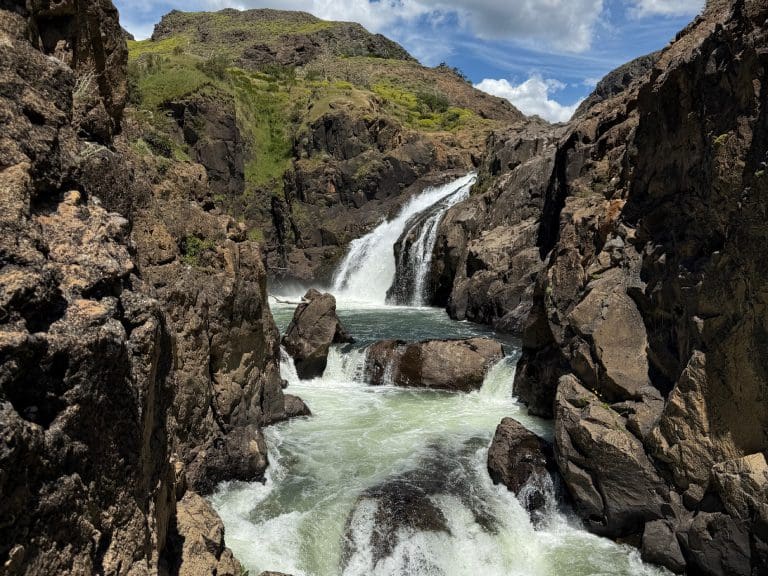 Rocky waterfall under a bright blue sky.