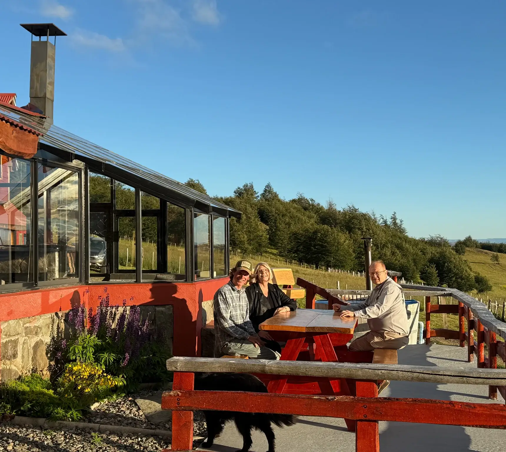 People enjoying drinks outdoors at a sunny cafe with a scenic view.