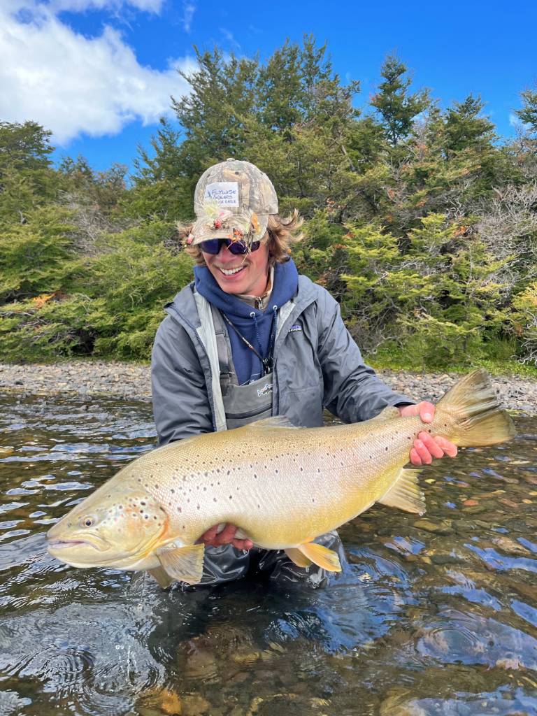 Man proudly holding a large fish outdoors.